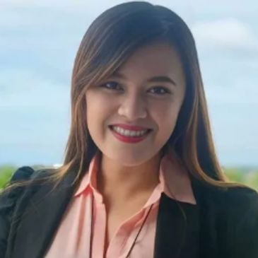 Smiling woman in business attire with a natural background.