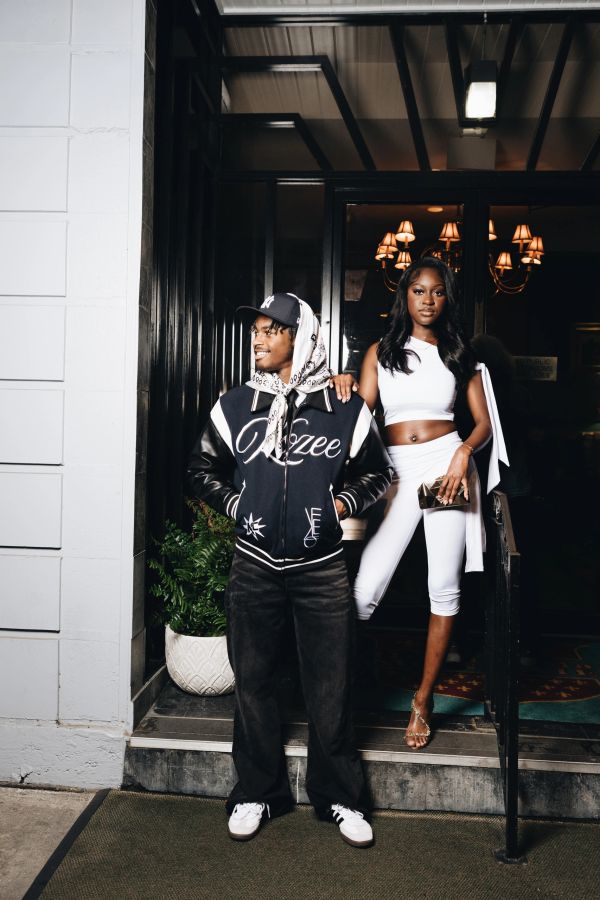 Stylish young couple posing outside a building entrance at night.