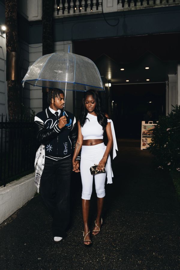 Couple walking hand in hand under an umbrella at night.