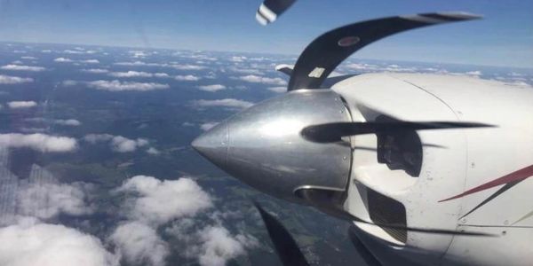 airplane propeller in action above the clouds, photo taken from the inside of the plane looking out