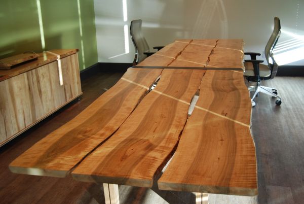 Long wooden conference table with natural edges in a modern office space.