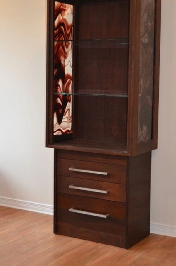 Tall wooden cabinet with glass shelves and abstract side panels.