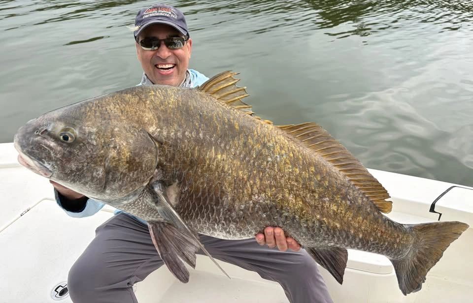 Man holding a large fish on a boat.