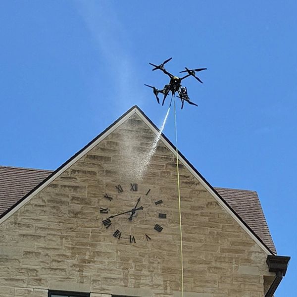 A drone is cleaning the exterior facade of the building at the inaccessible spot.
