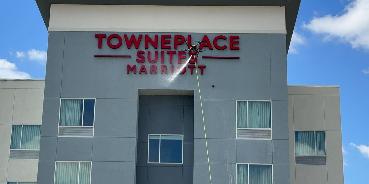 Drone spraying on the facade of the TownePlace Suites Marriott building, drone facade cleaning