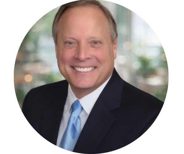 Smiling man in suit and blue tie.