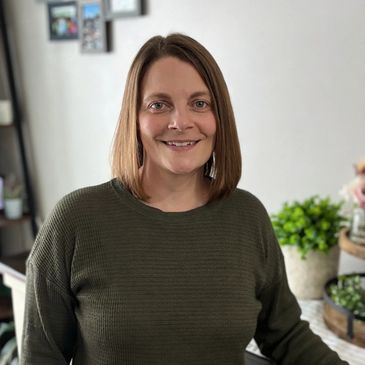 A woman with shoulder-length hair smiling indoors.