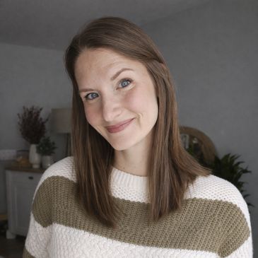 Smiling woman in a cozy striped sweater indoors.
