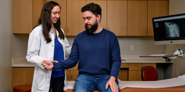 Doctor examining patient's wrist in a medical office.