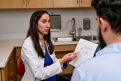 Doctor explaining a medical diagram to a patient in a clinic.
