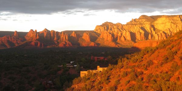 Sunlit red rock formations in a desert landscape at sunset.