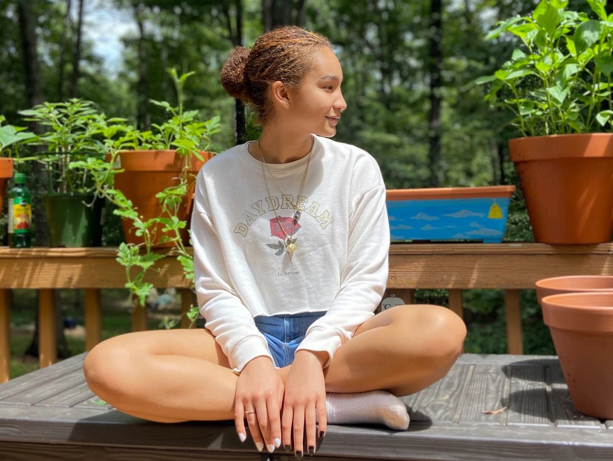 Beautiful girl sits in garden in sun wearing  MyTalow beef tallow balm SPF hypoallergenic 