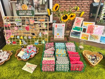 Kraam met stickers, kaarten en bloemen op groene tafel.