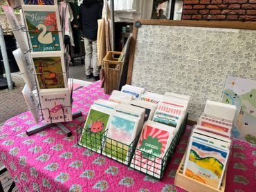 Een markttafel met ansichtkaarten en een wenskaartenhouder.