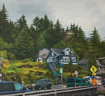 A street scene with cars and houses on a grassy hill surrounded by trees.