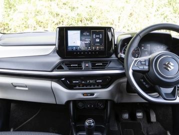 Interior view of a Suzuki car dashboard with touchscreen and manual gear shift.
