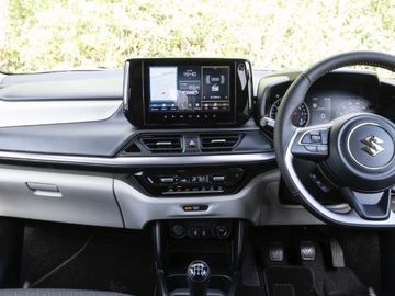 Interior view of a Suzuki car dashboard with touchscreen and manual gear shift.