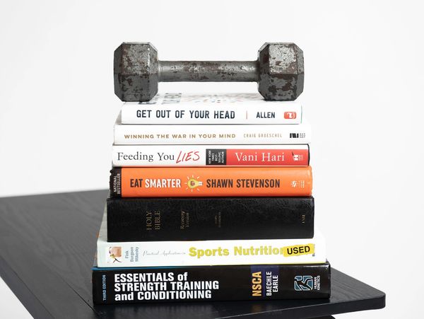 Stack of educational book, The Bible and a weight 