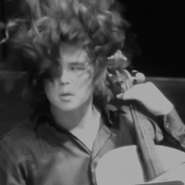 Black and white photo of a person intensely playing a string instrument.