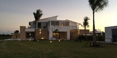 Casa moderna al atardecer con jardín y palmeras.