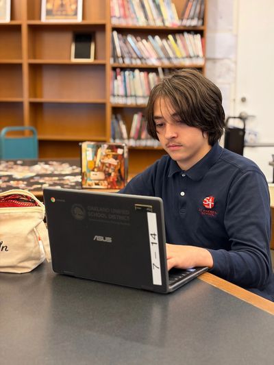 A student focused on his laptop in a school library.