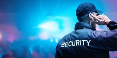 Security guard monitoring a crowded event with a communication earpiece.
