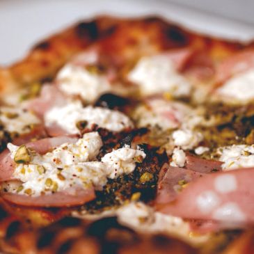 Close-up of a pizza with white cheese and ham.