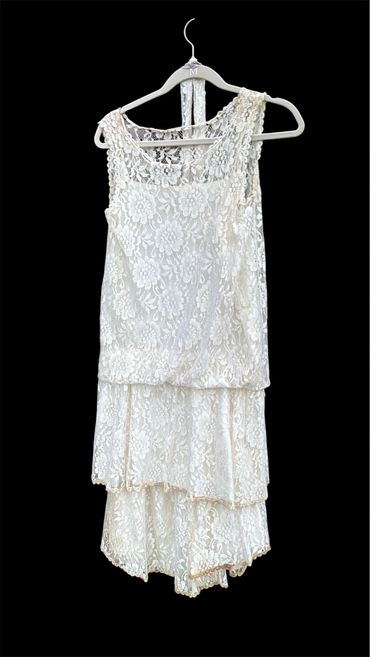 Elegant white lace dress with floral patterns on a hanger.