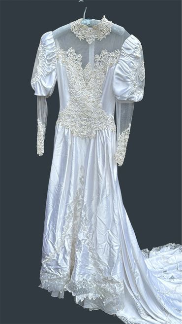 Vintage white satin wedding dress with lace details and puffed sleeves.