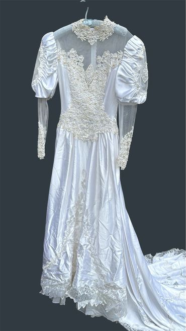 Vintage white satin wedding dress with lace details and puffed sleeves.