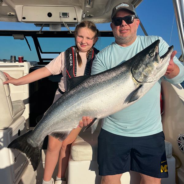 Man and girl holding a large fish on a boat.