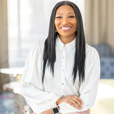 Smiling woman in white blouse sitting indoors.