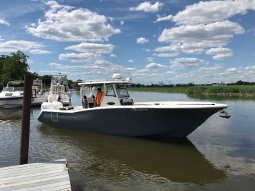 A sleek motorboat docked on calm water under a partly cloudy sky.