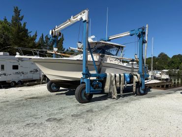 Boat being lifted by a blue boat hoist on a sunny day.