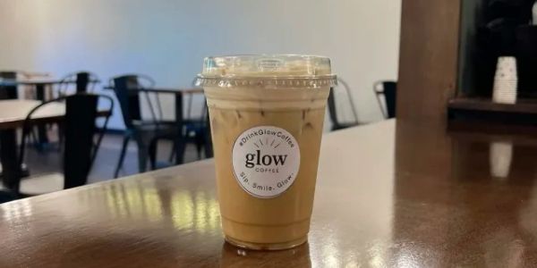 Iced coffee in a clear plastic cup on a wooden table.