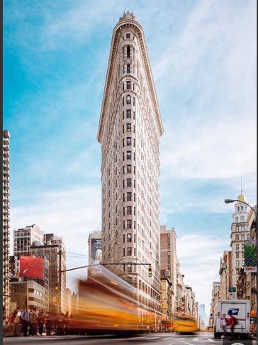 The iconic Flatiron Building in New York with blurred yellow taxis speeding by.