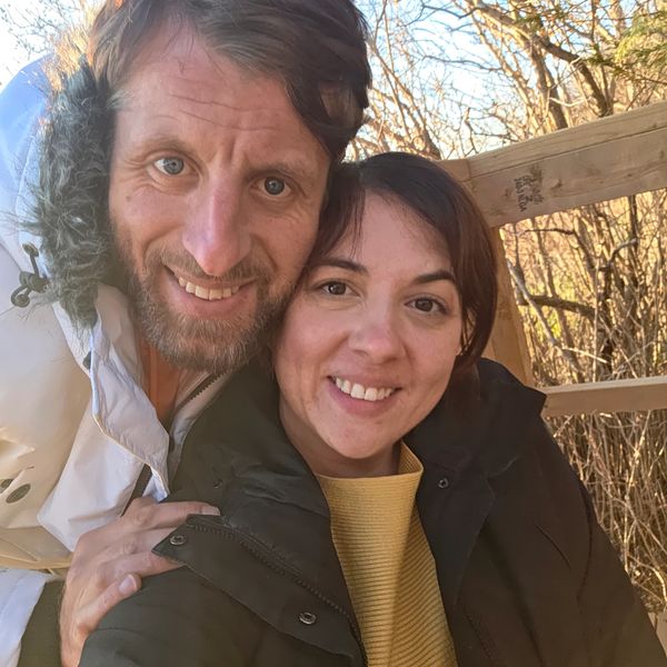 Smiling couple outdoors in warm jackets on a sunny day.
