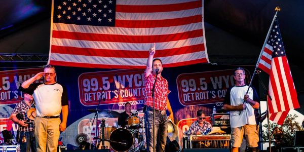 Band performing on stage with American flags and a man saluting.