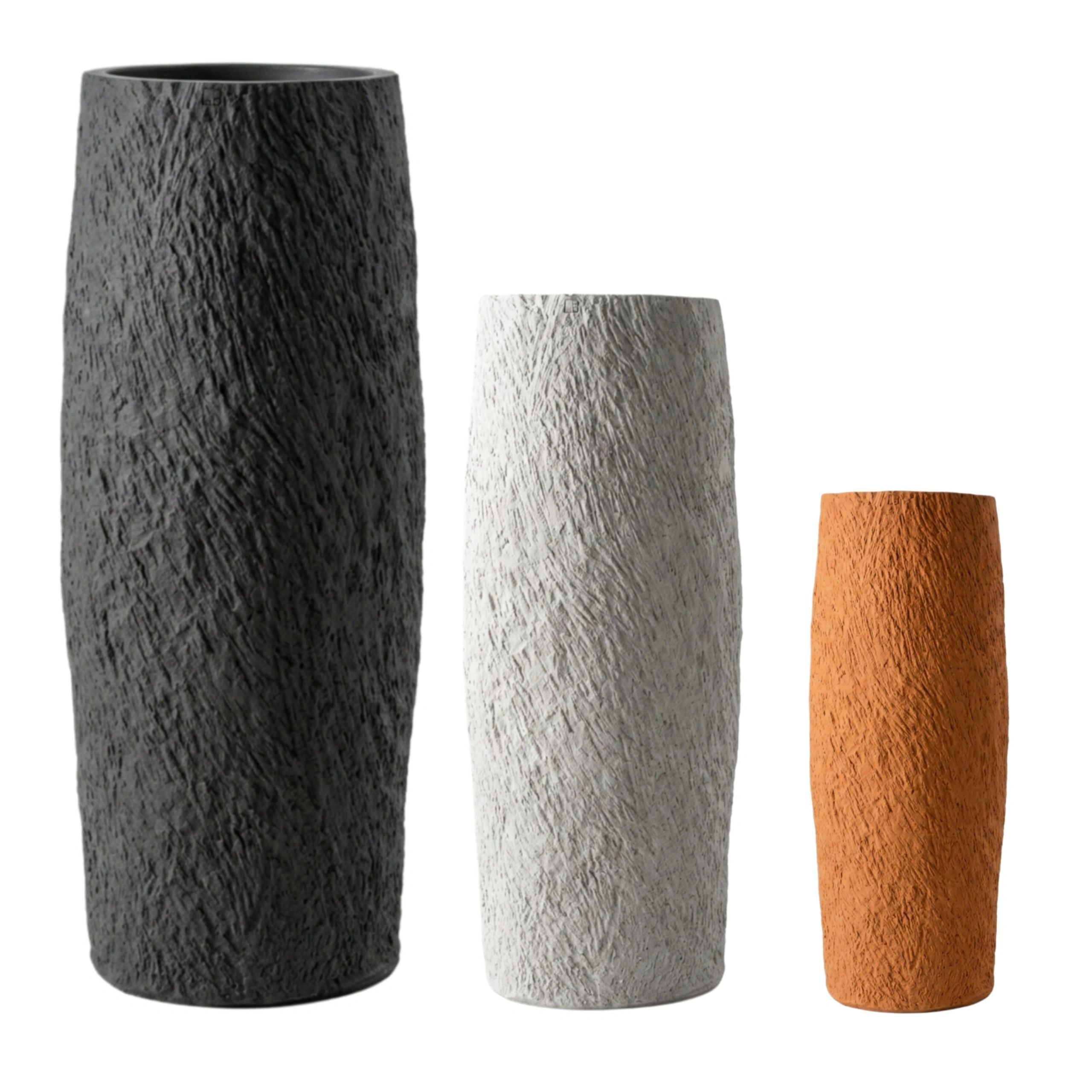 Three textured cylindrical vases in black, white, and terracotta colors.