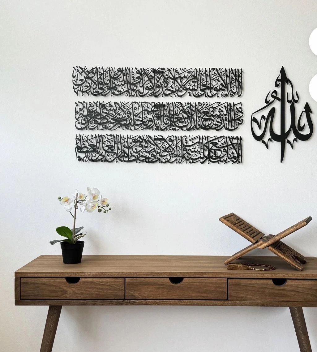 Minimalist wooden desk with Islamic calligraphy and a small orchid plant.