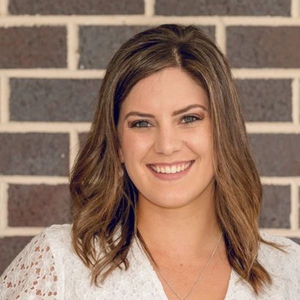 Jessica the naturopath a women wearing white with a brick wall background 