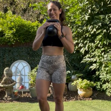 Woman exercising outdoors with a kettlebell in her hands.