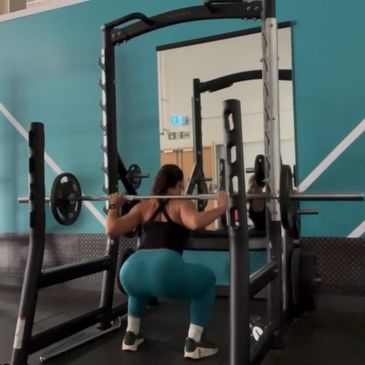 Woman doing barbell squats in a gym.