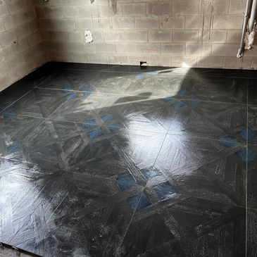 Newly installed dark patterned floor tiles in an unfinished room.