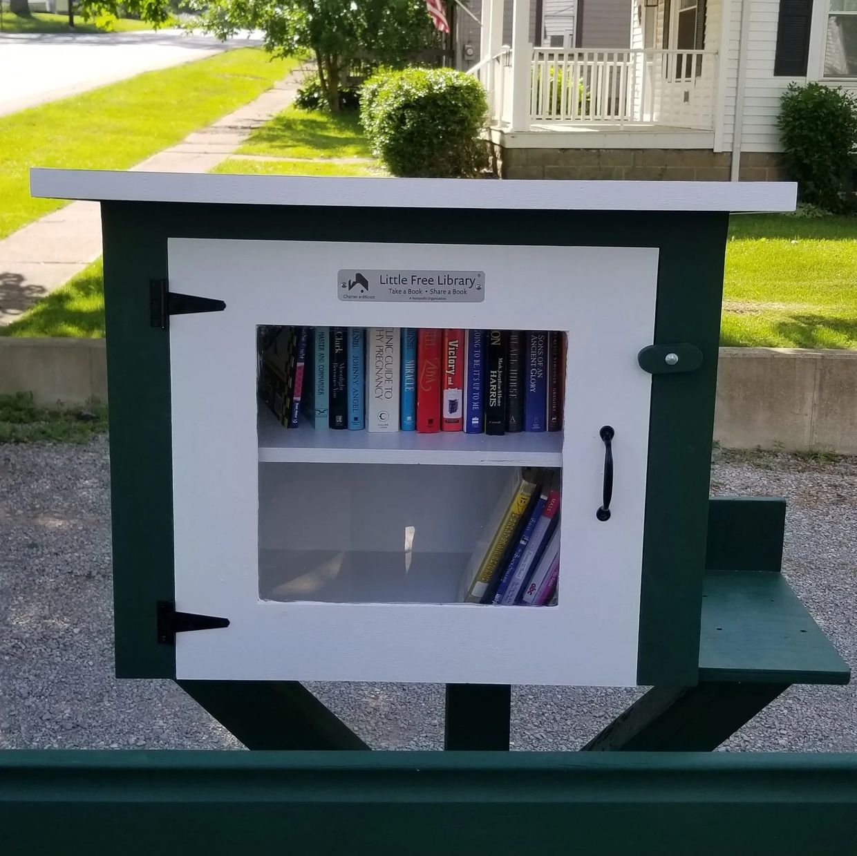 A green Little Free Library with a white door