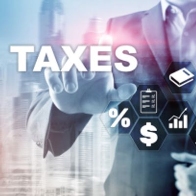 Businessman pointing at the word TAXES with financial icons around.