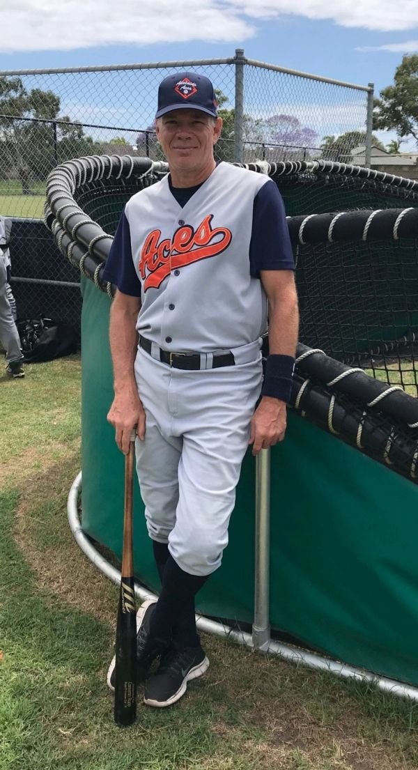 Man in baseball uniform holding a bat on a baseball field.