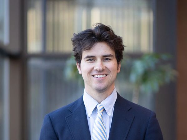 Young man in a suit smiling at the camera.