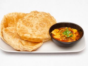 Plate of Indian puris with a bowl of spicy curry.