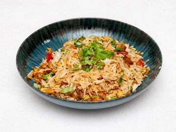A bowl of fried rice garnished with fresh herbs.